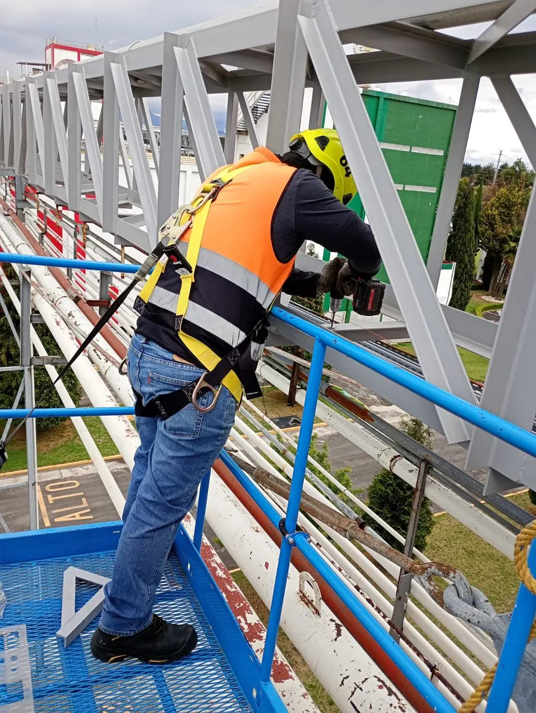 Técnico con equipo de seguridad instalando estructura industrial en altura